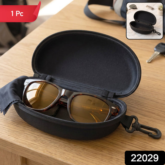 An open black hard shell sunglasses case with brown sunglasses and a black cleaning cloth inside, on a wooden table