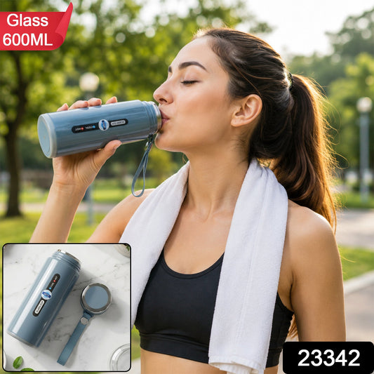 A woman in athletic wear drinks from a blue insulated bottle with a white towel around her neck outdoors. – view 2