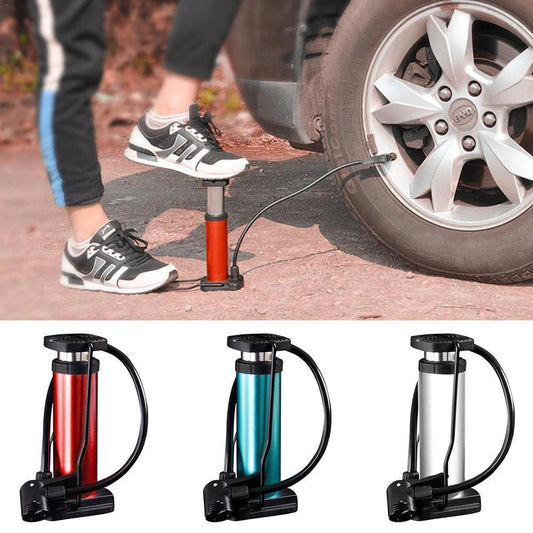 Person using a red mini foot pump to inflate a car tire outdoors.