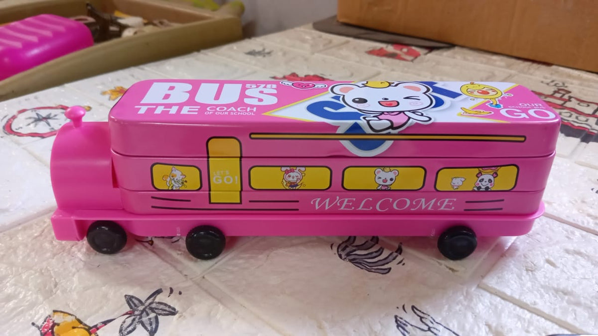 Pink bus pencil case with a cartoon bear on top, resting on a patterned white and brown surface.