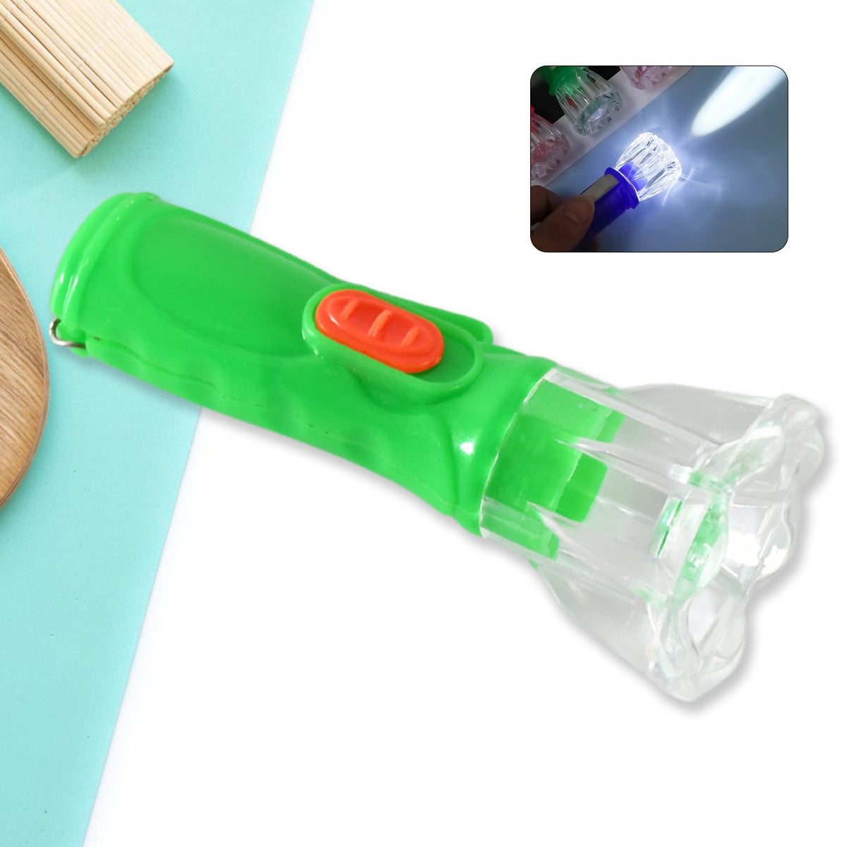 A green and orange plastic flashlight with a clear faceted head is shown on a blue and white background with an inset of it