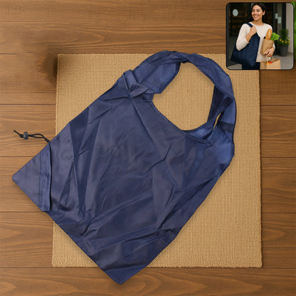 A dark blue reusable shopping bag lies on a brown mat, with an inset image of a woman carrying a similar bag.