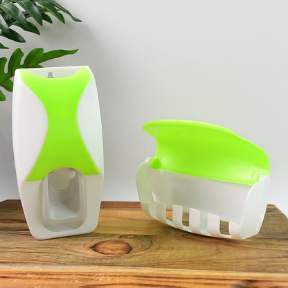 The white and lime green automatic toothpaste dispenser and toothbrush holder, separated, on a wooden surface with a plant