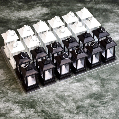 Twenty-four small black and white LED candle lanterns, arranged in rows on a clear plastic tray.