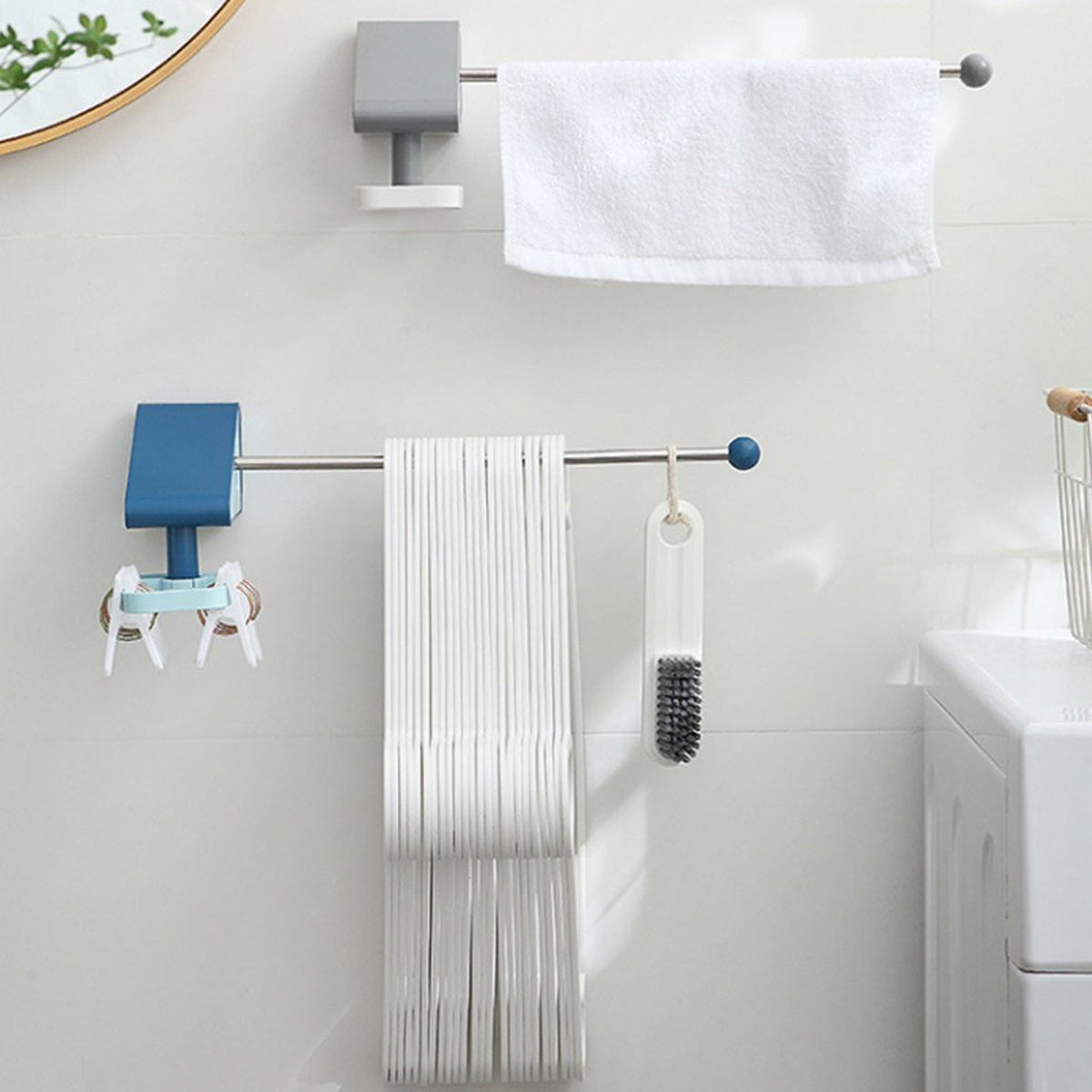 Two wall-mounted racks, one blue and one grey, holding hangers, keys, a brush, and a white towel in a bathroom.
