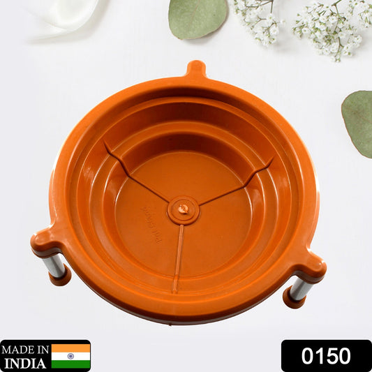 Overhead view of an orange plastic stand with three silver legs, on a white surface with green leaves.