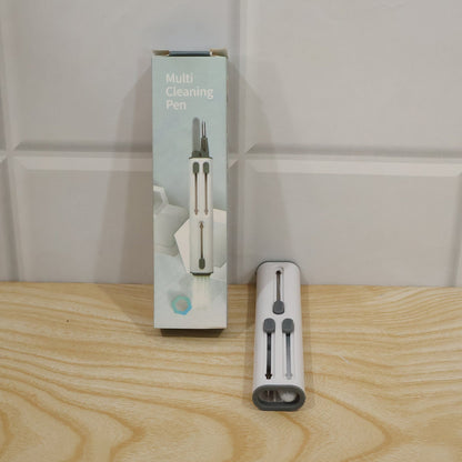 The multi-tool cleaning pen next to its light blue and white retail packaging on a wooden surface.
