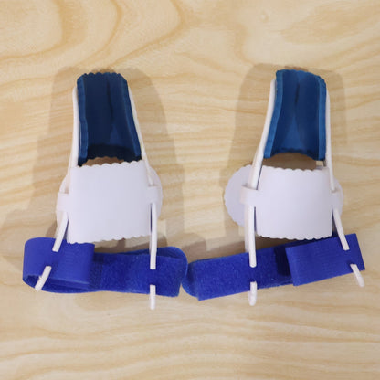 Two blue and white toe splints with blue straps are placed side by side on a light wooden surface.
