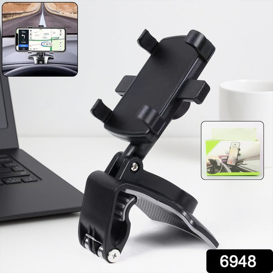 Black phone holder clipped to a car dashboard with a phone showing navigation, next to a laptop and mug.