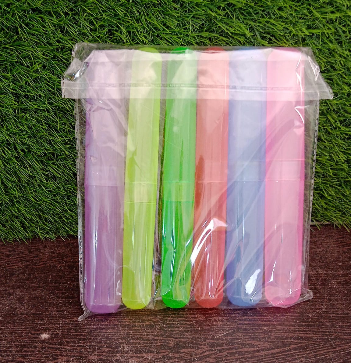 Six colorful translucent toothbrush cases are packaged together in clear plastic, standing upright on a textured surface.