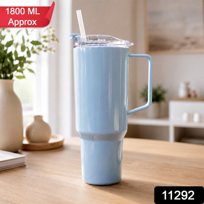 A light blue travel tumbler with a handle and straw sits on a wooden table, with