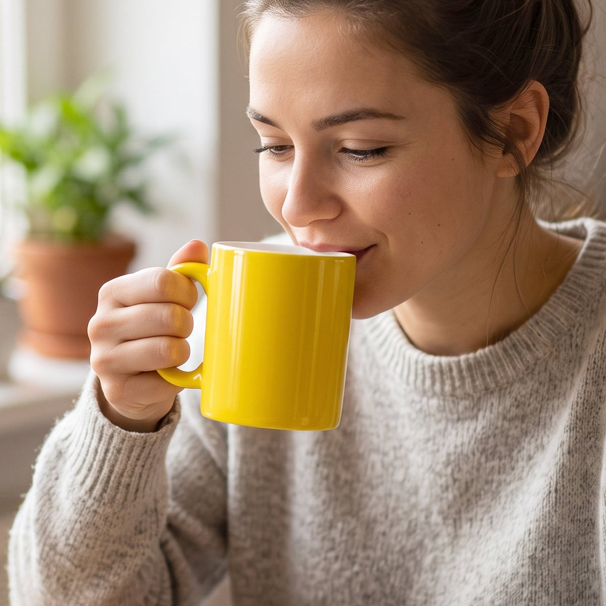 A yellow mug with a white interior stands next to a white box labeled "Gift with Love Coffee Mugs" on a wooden surface.