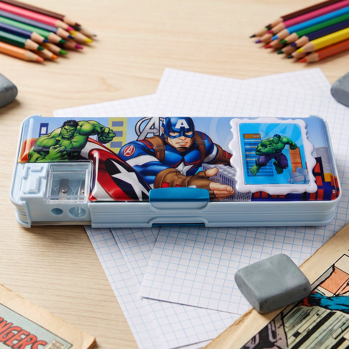 A close-up of a light blue pencil box with Avengers graphics, a sharpener, and a small calculator on a wooden desk.