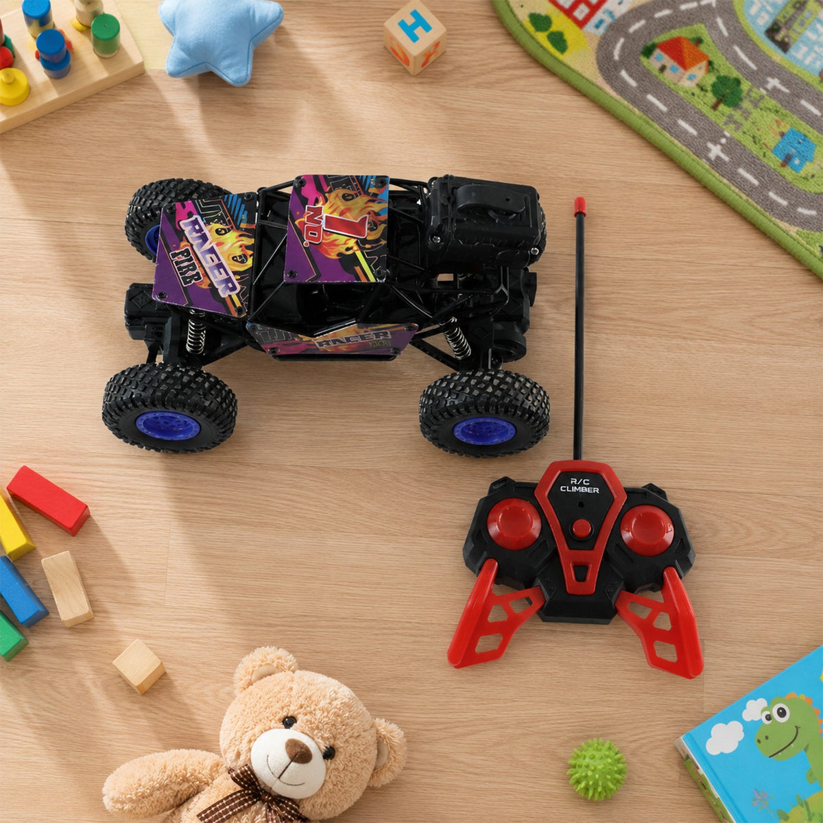 A black and purple remote control rock crawler and its red and black remote are on a wooden floor surrounded by children's