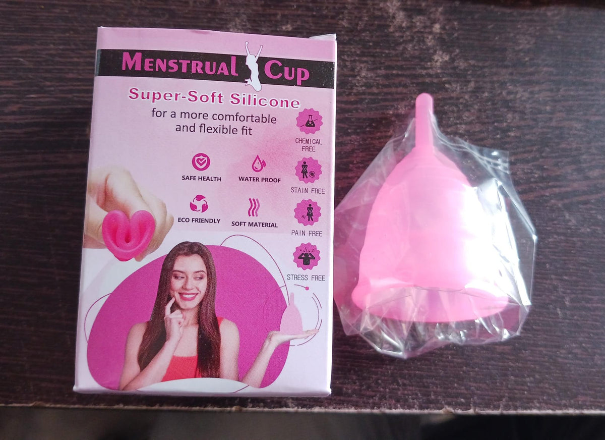 A pink silicone menstrual cup is shown on a white background, highlighting its flexible and soft material.